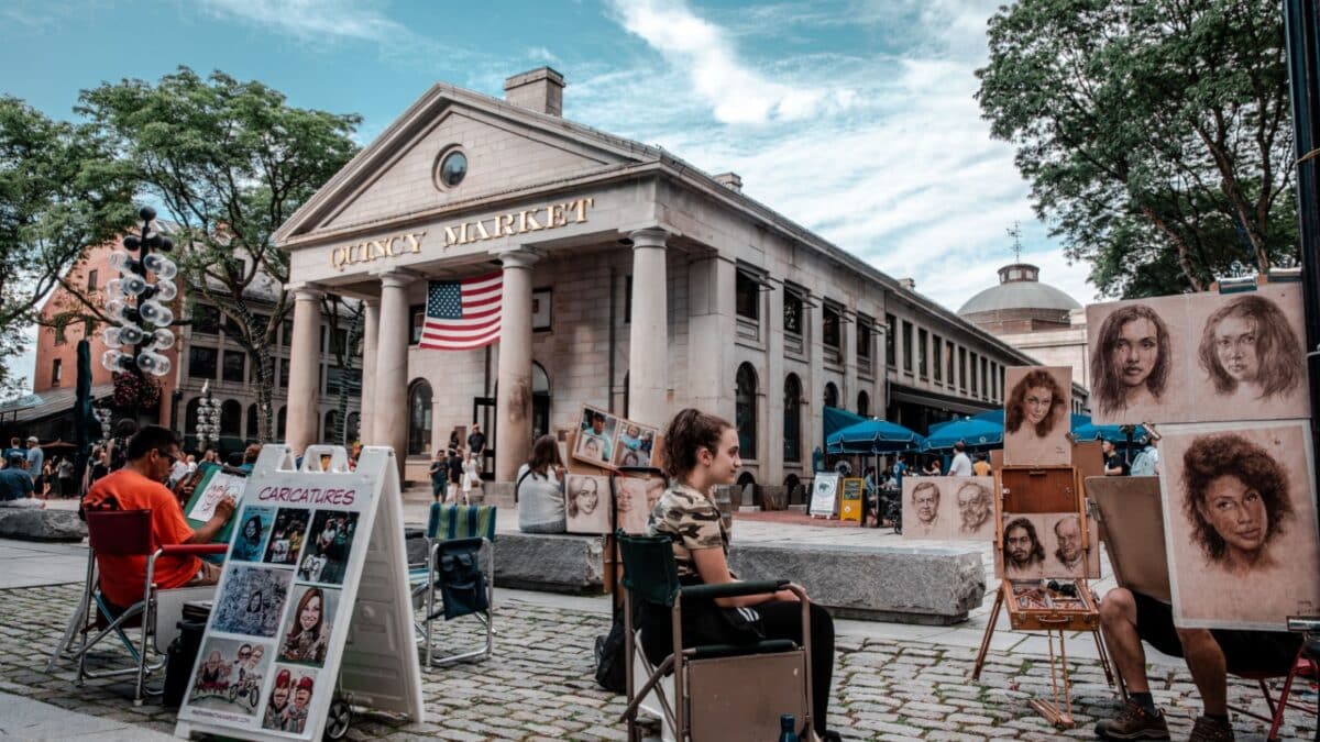 BOSTON - JULY 12: Artist drawing tourists at Quincy Market on July 12, 2019 in Boston. Quincy Market dates back to 1825 and is a major tourism destination in Boston.